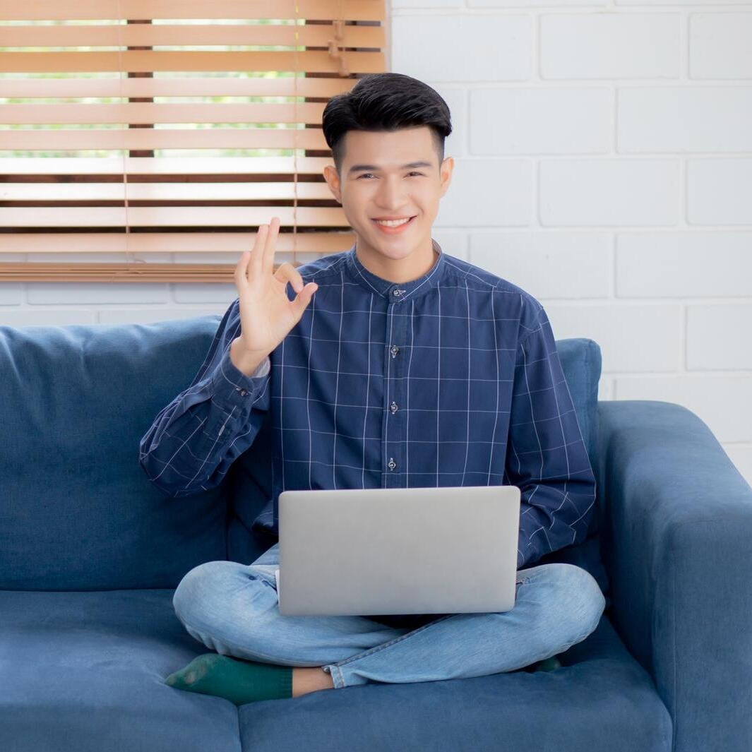 Young asian businessman smile and work from home with laptop